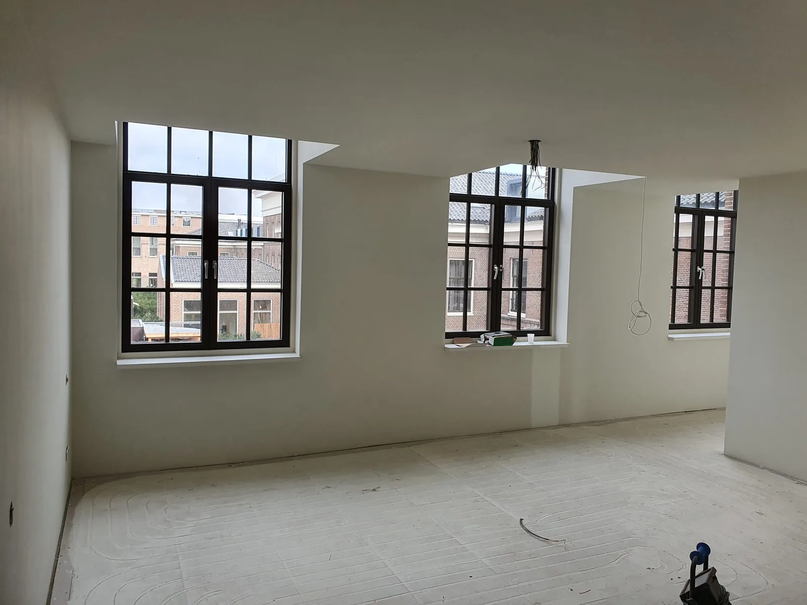 Lichte wanden en plafond in een ruimte met drie zwarte raamkozijnen