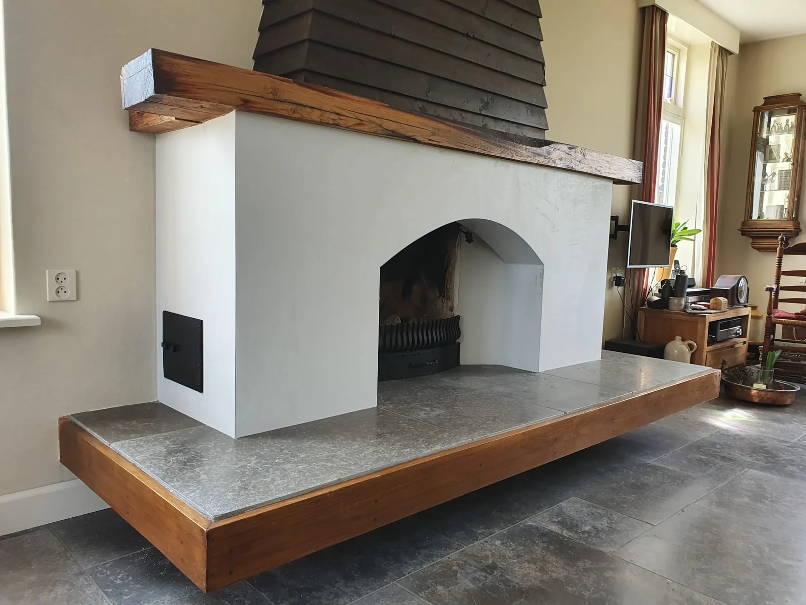 Licht afgewerkte schouw met een ronde opening en houten bovenrand
